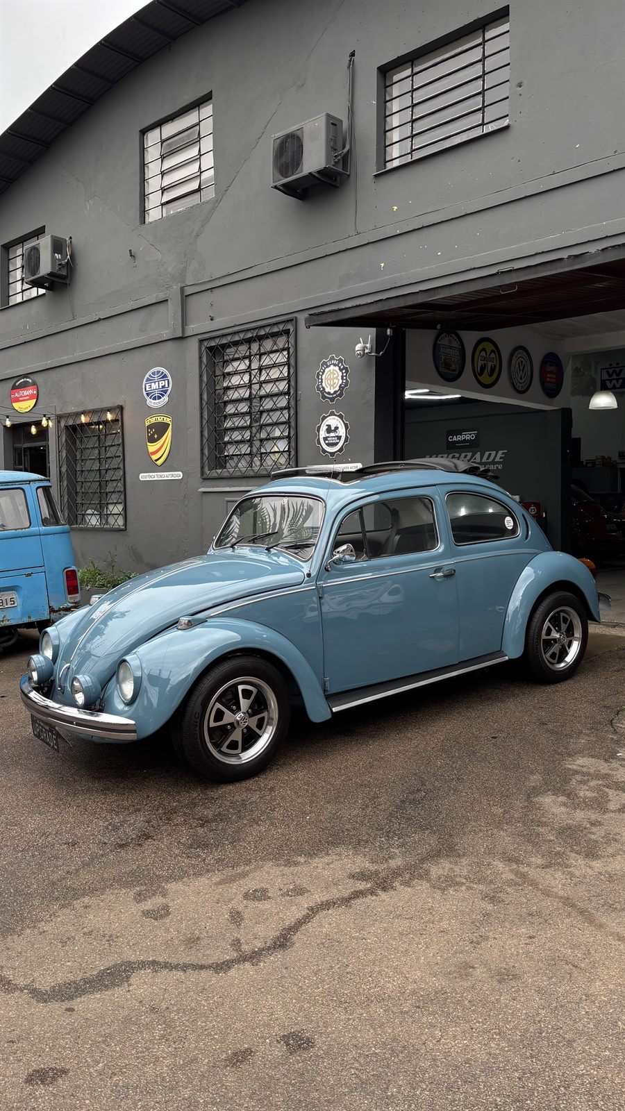 Fusca azul-claro em frente à fachada da oficina