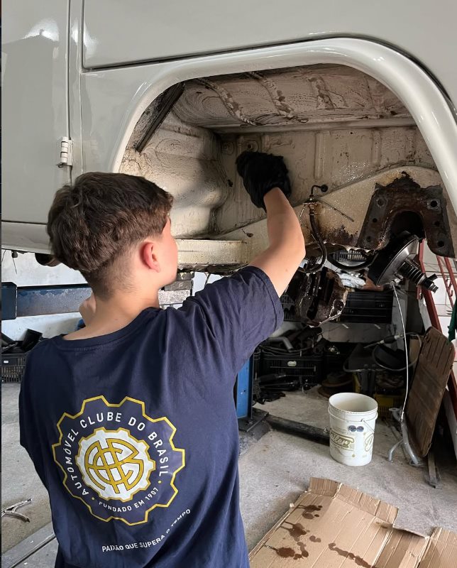 Mecânico trabalhando na caixa de roda de uma Kombi na oficina